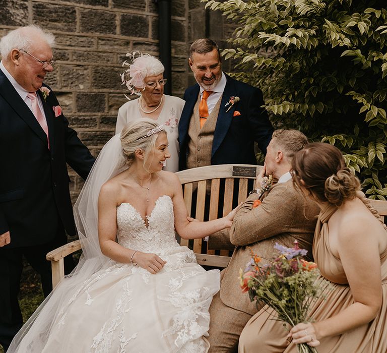 Bride and groom and other family members sit on a bench in memory of lost loved one