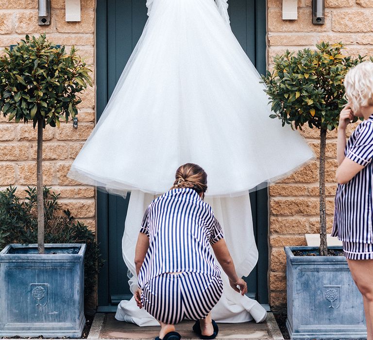 Tulle princess skirt wedding dress with ruffles and detachable sleeves on white satin hanger in front of front door