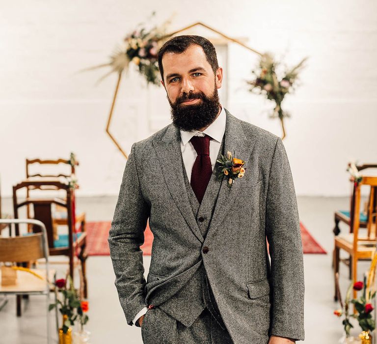 Groom in grey three piece suit with a burgundy tie and yellow flower buttonhole 