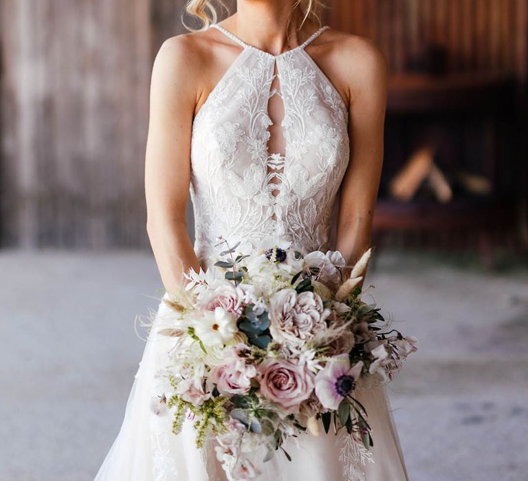 Bride in tulle halter neck wedding dress with a keyhole cut holding pink and white flower bouquet  