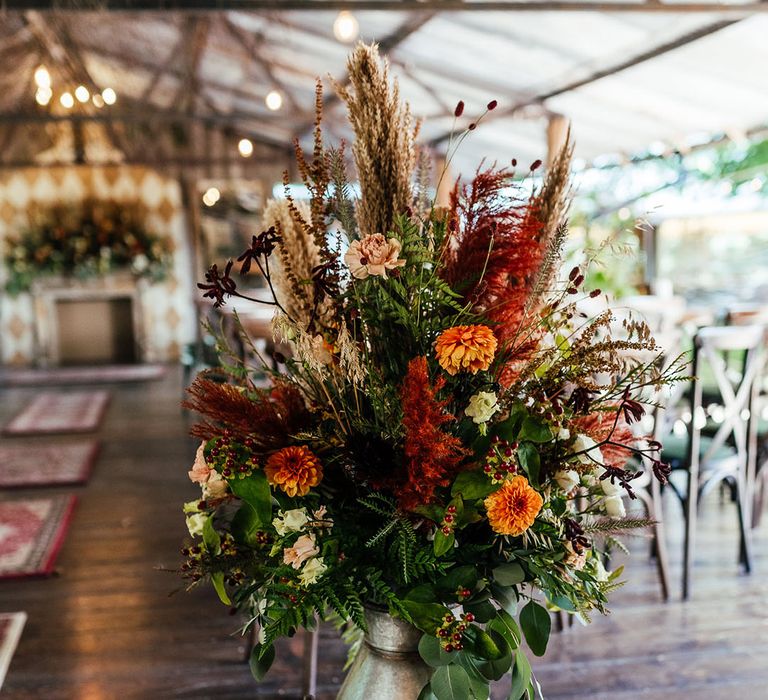 Warm toned wedding flowers in a metal vintage milk churn for wedding decor 