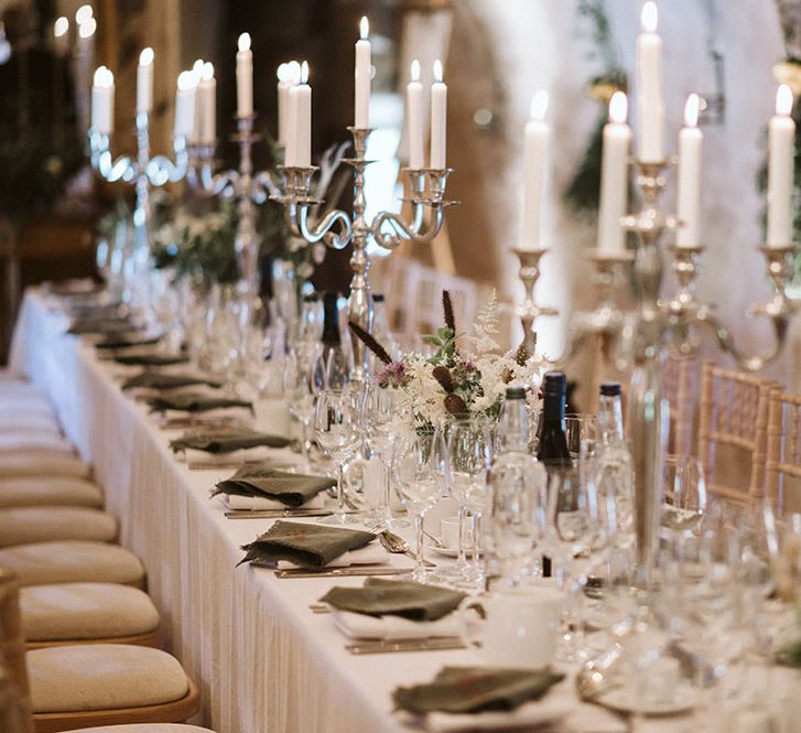 Classic tablescape complete with candles, homemade embroidered napkins and small floral arrangements 