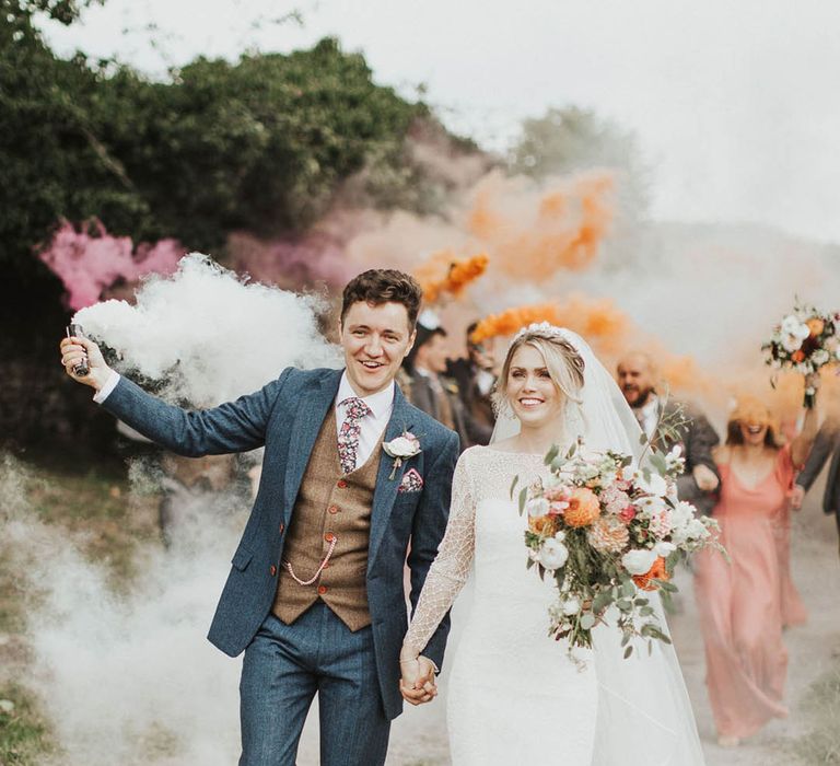 Bride and groom walk with their hands intertwined for their smoke bomb couple portrait 