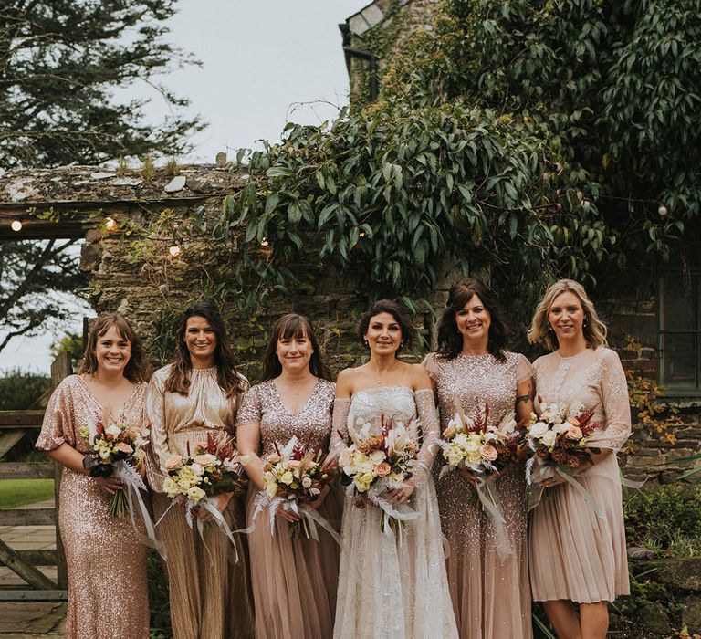 Pink metallic, sequinned and sparkly bridesmaid dresses standing with the bride in a sparkly wedding dress 