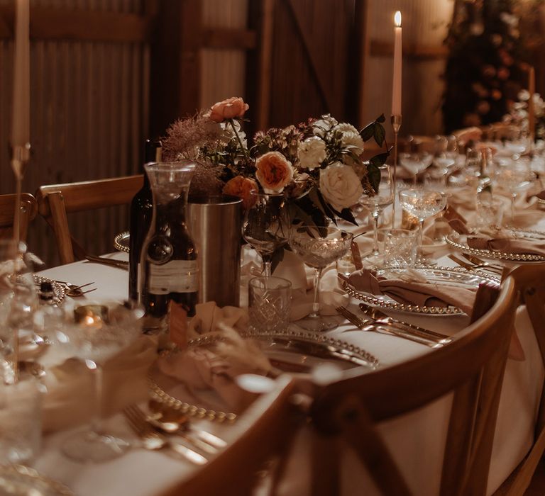 Pink and white flower arrangements, gold cutlery, gold edged charger plates, pink and grey stationery and a blush napkin and table runner romantic tablescape