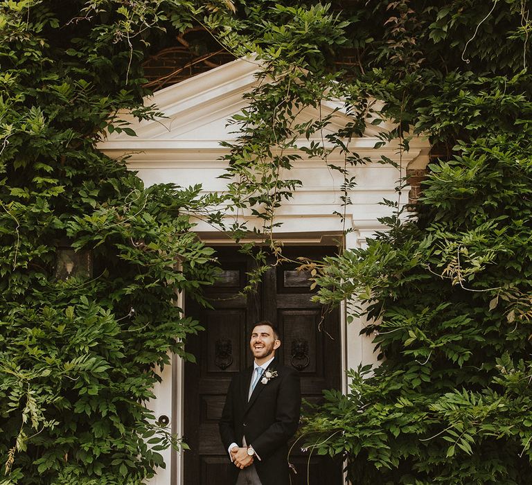 Groom in morning suit with a pale blue tie, grey waistcoat and pinstriped trousers for the classic wedding 