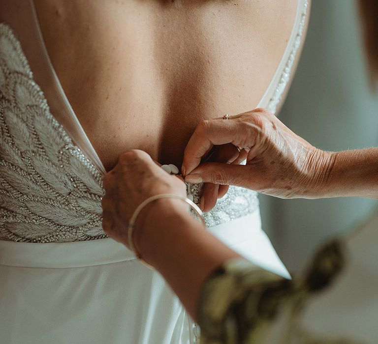 Bride gets buttoned into her wedding dress with sparkly details 