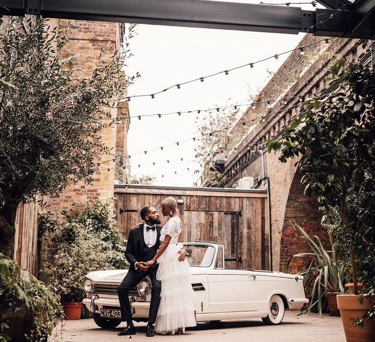 Black Bride and Groom at London wedding venue, 100 Barrington, posing with classic vintage wedding car