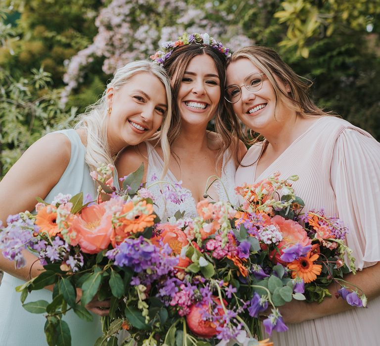 Bride stands with her bridesmaids holding colourful floral bouquets filled with peonies 