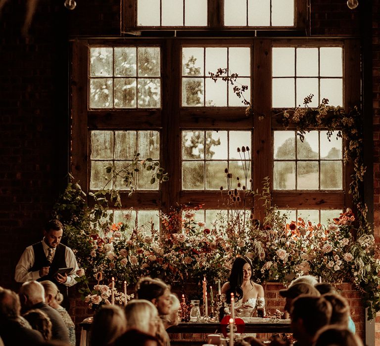 Wedding party and guests sitting in the reception room of The Giraffe Shed wedding venue doing wedding speeches 