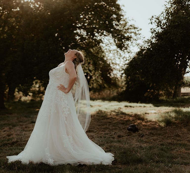 Bride wears lace wedding dress and tulle skirt during golden hour portraits 