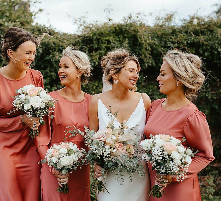 Bridesmaids in long sleeve satin rose-coloured midi bridesmaid dresses for the rustic luxe wedding 