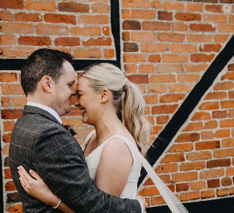 Bride in floral lace Karen Willis Holmes wedding dress with tulle wings embracing the groom on their wedding day 