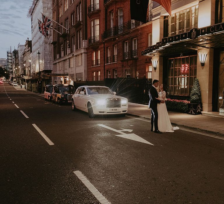 Bride in lace long sleeve Pronovias wedding dress gazing up at the groom at the front of the Claridge's wedding venue 