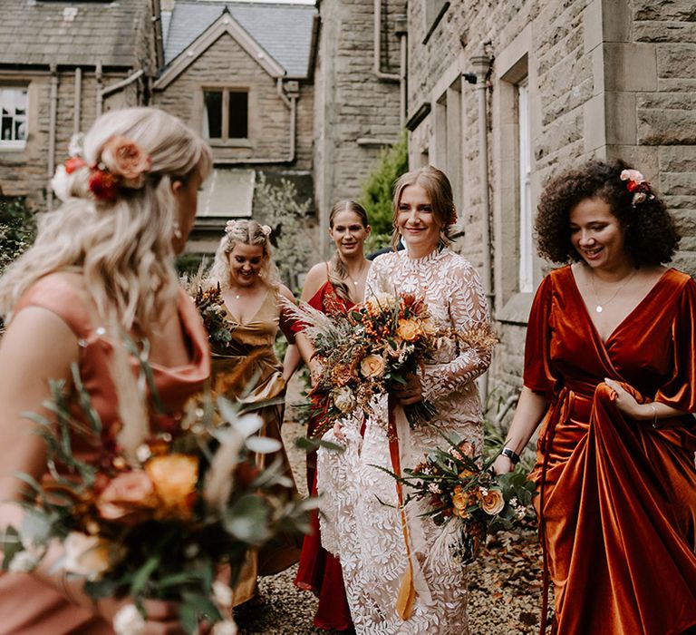 Bridesmaids in mismatched bridesmaid dresses in warm toned autumnal shades for the pumpkin patch wedding 