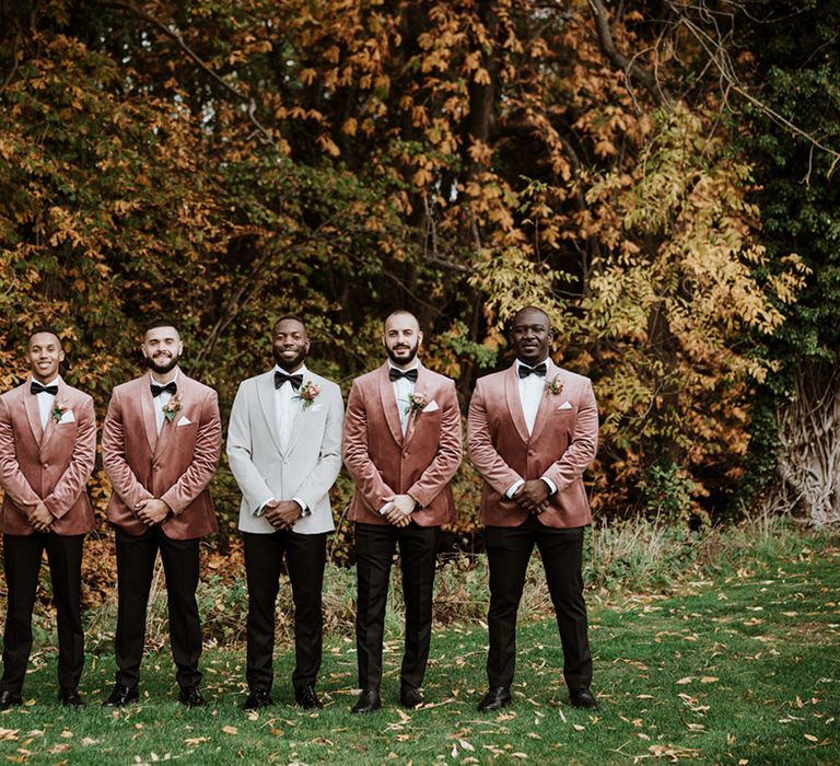 Groomsmen in blush pink crushed velvet suits with the groom in a grey suit jacket for the wedding at Colville Hall 