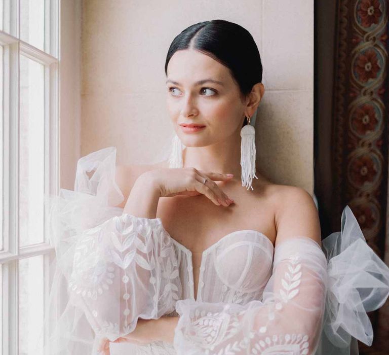 Bride at Notan inspired bridal editorial at Settrington Orangery wearing sweetheart neckline tulle mesh bridal gown with detachable puff tulle sleeves and delicate beading with cathedral length veil 