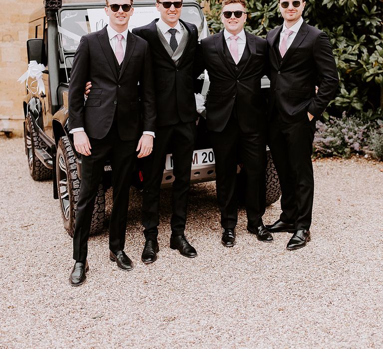 Groomsmen in black suits with pink ties wearing sunglasses for the wedding day 