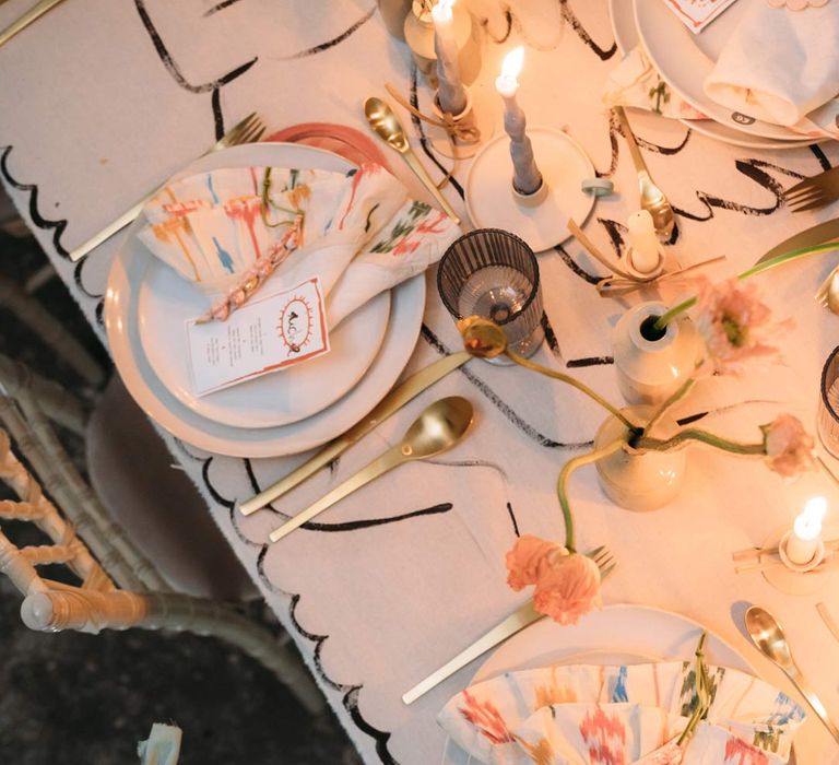 Eclectic abstract wedding tablescape at Margate Caves - neutral toned under table cloth, abstract design wedding tablecloth on top, twisted tapered candles in ceramic candlestick holders, gold cutlery, abstract wedding stationery, and dried flower centrepieces