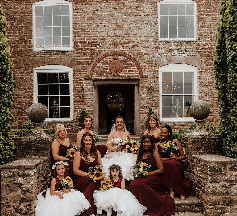 Bridal party wearing red bridesmaid dresses with the flower girls in faux fur shawls 