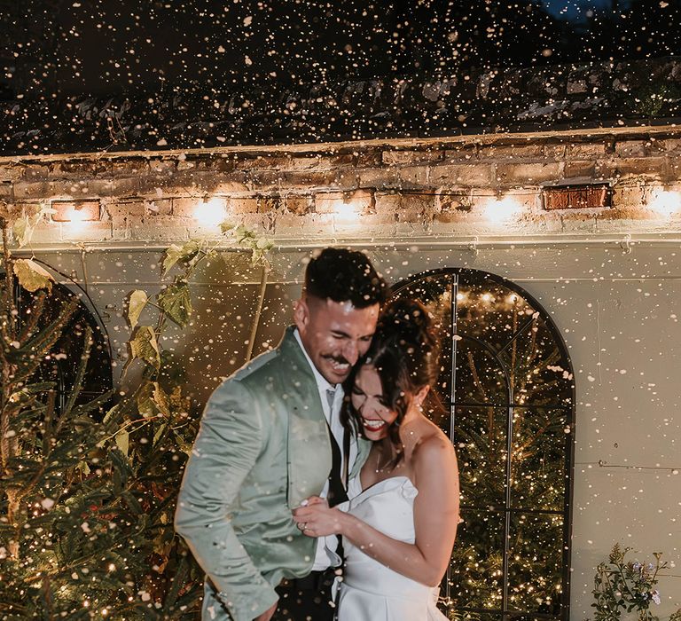 Fun and romantic snowy wedding couple portrait next to a Christmas tree 