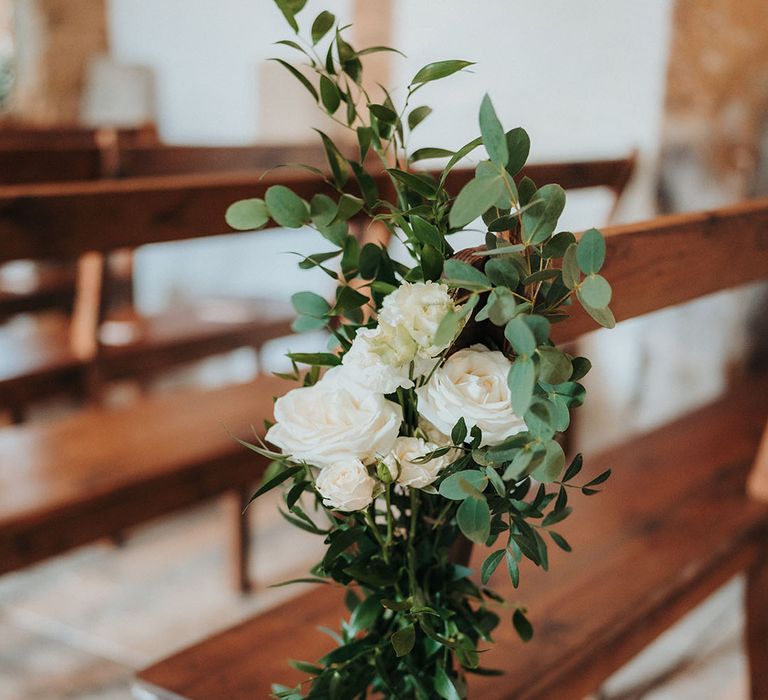 White rose wedding flowers decorating seating at the wedding ceremony 