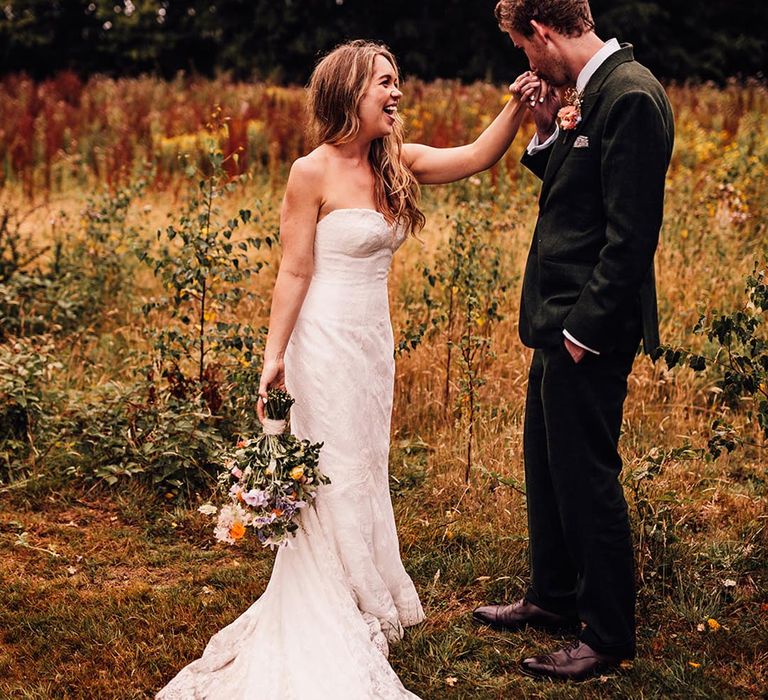 Groom in green suit kissing the bride's hand for romantic wedding couple portrait 