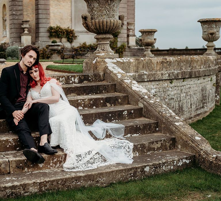 Bride and groom posing together on the steps of the wedding venue for couple portrait 