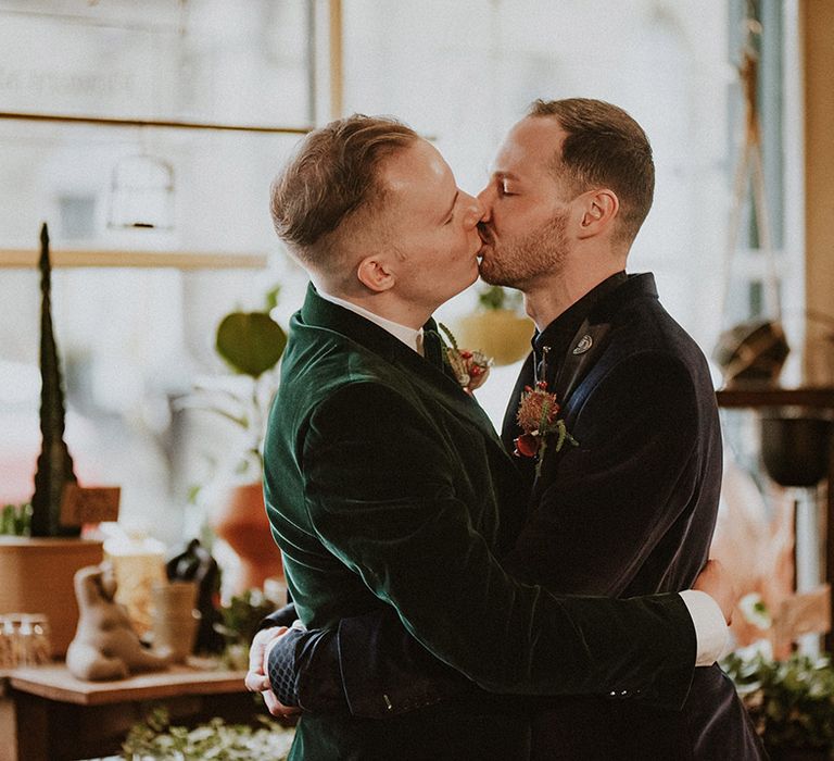 Same sex LGBQTIA+ wedding with two grooms sharing an intimate kiss on their wedding day with a spooky gothic theme 