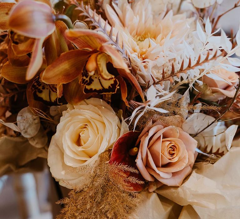 Boho autumnal wedding bouquet with roses, anthuriums, cafe au lait dahlias and foliage for autumn wedding in November 