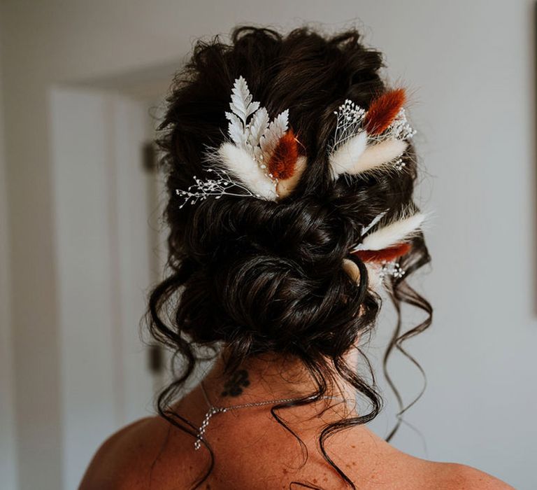 Bride with dark hair in an updo style with boho hair accessories and dried flowers 