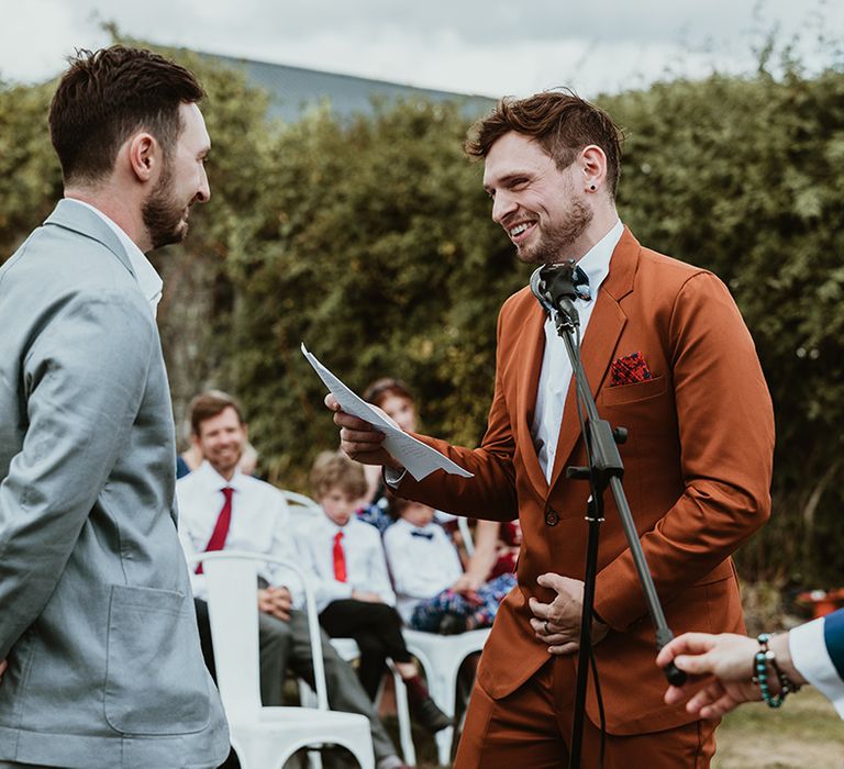 Two grooms exchange their wedding vows at outdoor wedding ceremony 