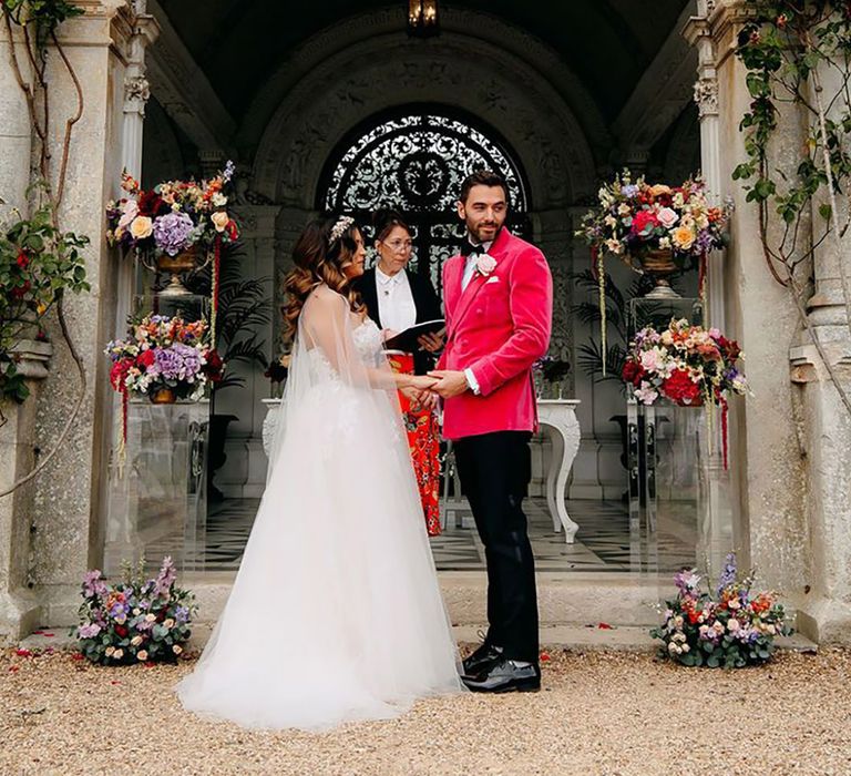 Bride in princess wedding dress with groom in pink velvet suit jacket