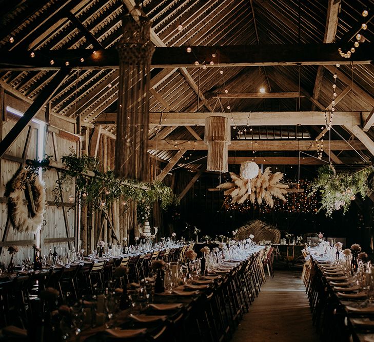 Barn wedding reception filled with rustic wedding decor, foliage and dried flowers 