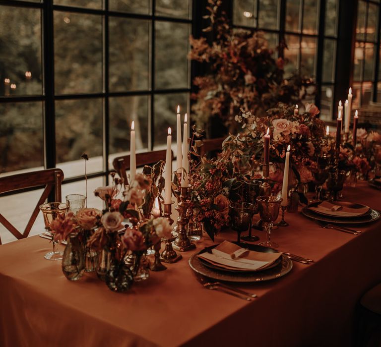 Place setting with gold charger plates and orange table cloth 