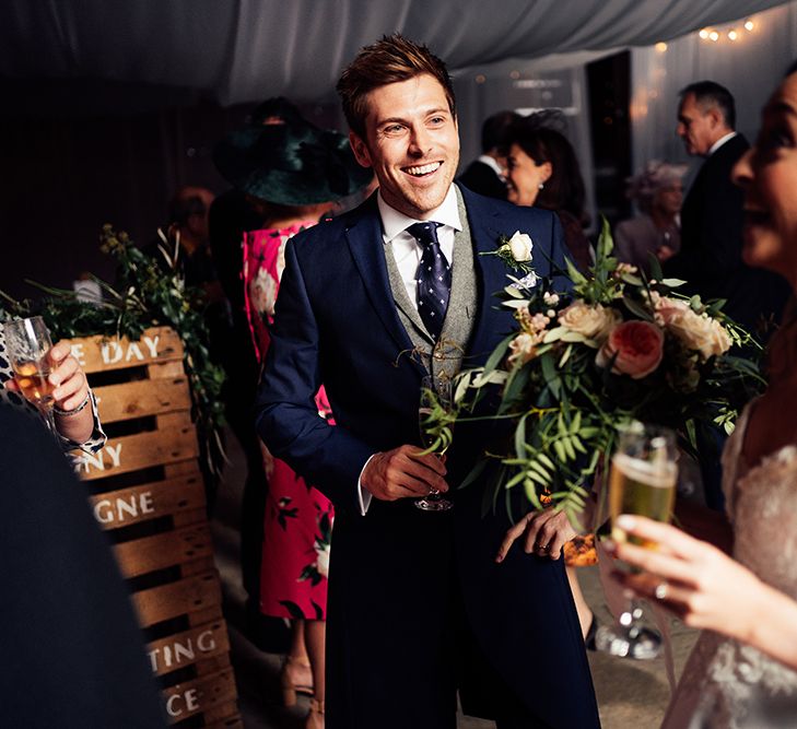 Grooms navy wedding outfit with peach roses 