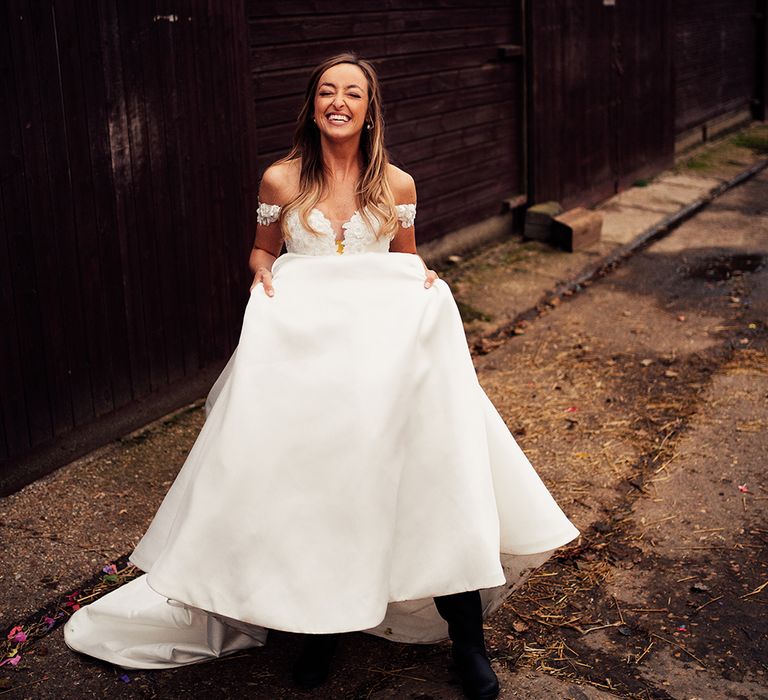 Bride smiling in her cold shoulder wedding dress for barn wedding 