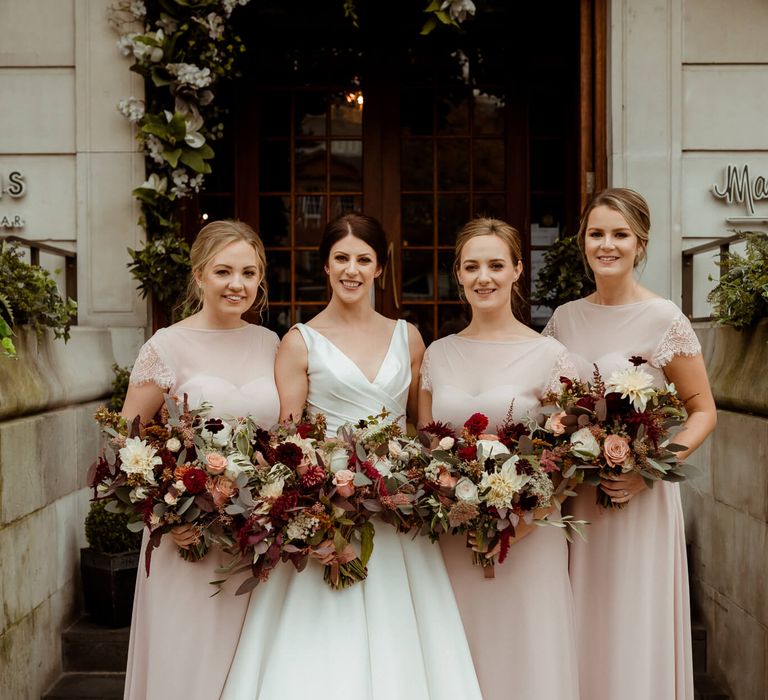 Bridal party wearing pink bridesmaid dresses and pink, red and white bouquets 