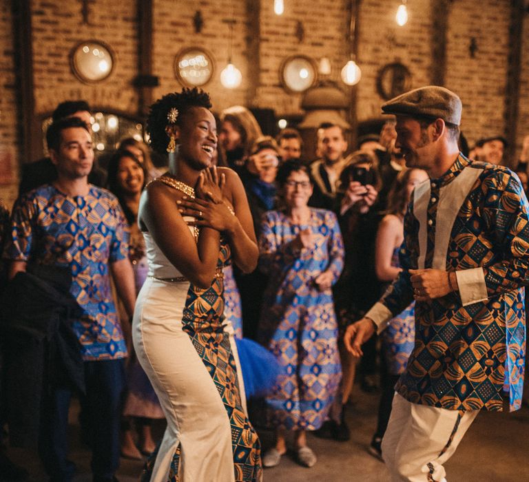 Bride and groom on the dance floor in matching traditional West African outfits with blue and gold tribal print 