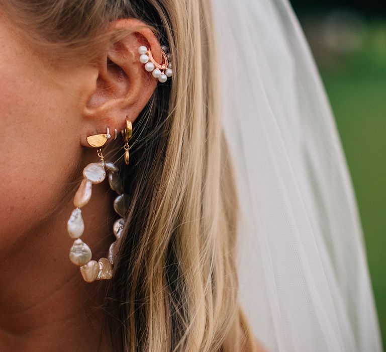 Bride wearing pearl earrings and matching hair accessories with blonde hair and white veil 