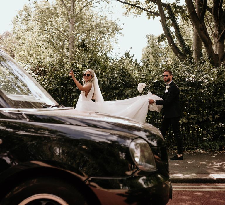 Bride & groom walk together through London and groom lifts brides train