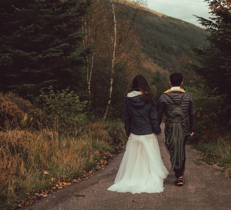 Couple walk together wearing jackets after rock climbing in Scotland