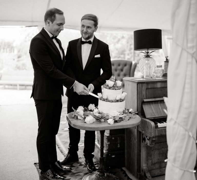 Grooms cut their cake on their wedding day for Oxford Town Hall wedding