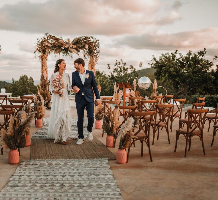 Outdoor bohemian wedding ceremony with rugs, dried flowers and terracotta pots 