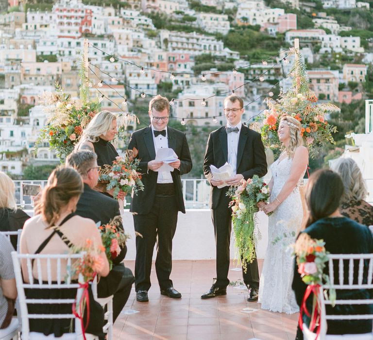 The two brides laughing during their ceremony, officiated by their brothers