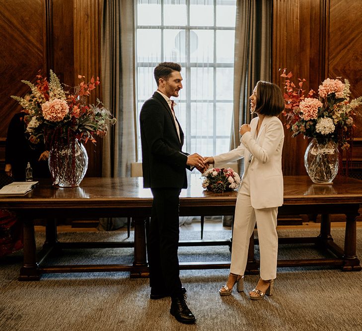 Bride & groom stand together in front of window after wedding ceremony