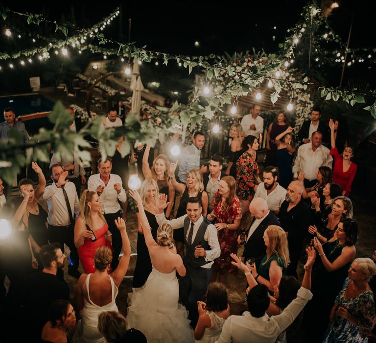 The whole wedding party dancing around the bride and groom on the dancefloor