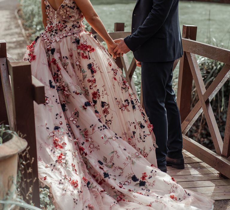 Bride & groom stand on wooden bridge on their wedding day