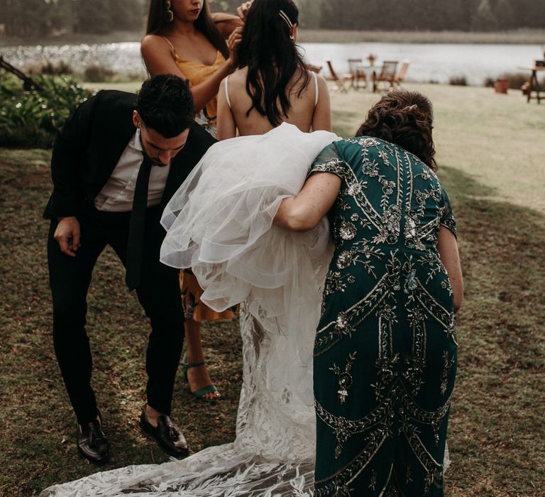 The groom, a bridesmaid and the mother of the bride helping the bride with her wedding dress