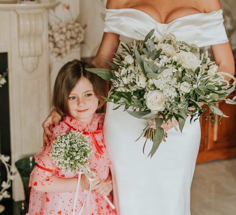 Cute flower girl with bride in off the shoulder wedding dress